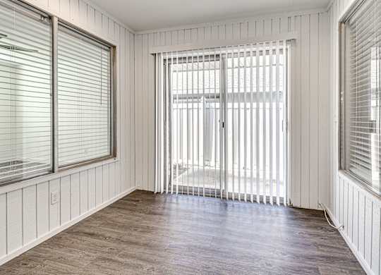 A room with wooden floors and white walls with a sliding glass door.