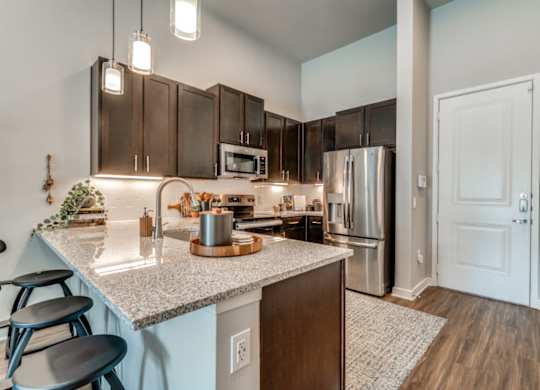 A kitchen with a granite countertop and stainless steel appliances.