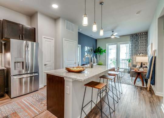 A kitchen with a refrigerator, stove, and bar stools.