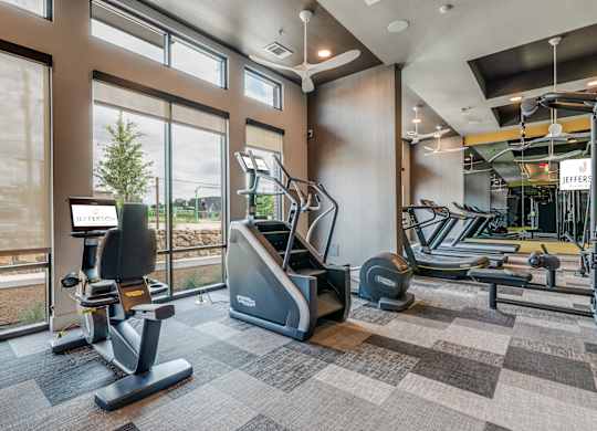 A JEFFERS brand treadmill is in a gym with a view of the outdoors.