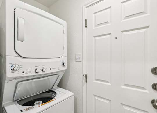 A white oven with a door open is in a room with a white door.