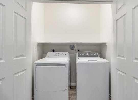 a washer and dryer in a laundry room with white walls and white doors