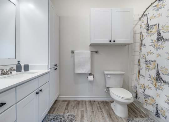 a bathroom with white cabinets and a toilet and a sink