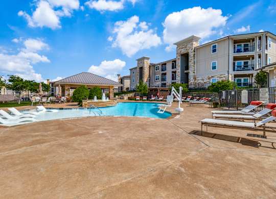a resort style pool with lounge chairs and a building in the background