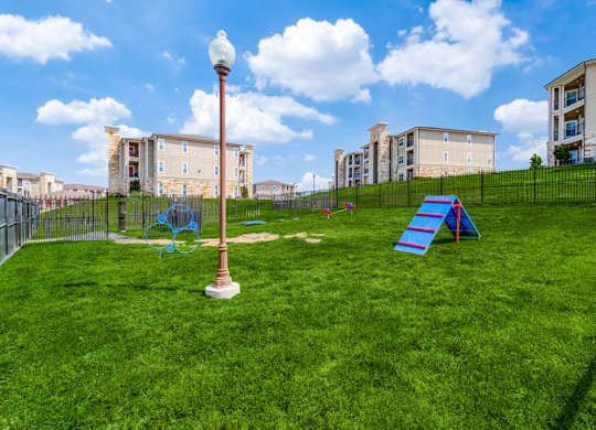 a playground on the grass with apartments in the background