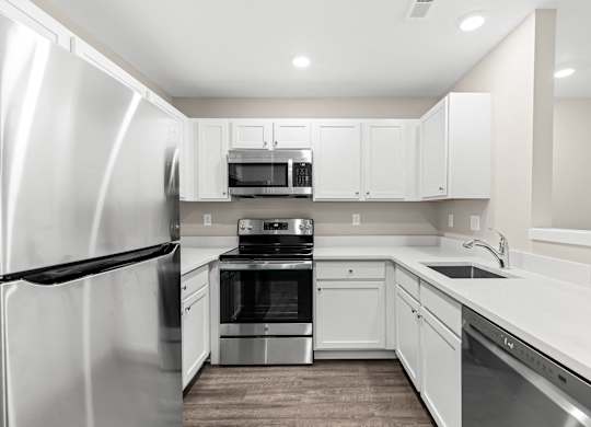 a white kitchen with stainless steel appliances and white cabinets