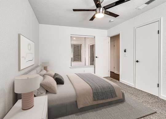 A bedroom with a bed, nightstand, and a ceiling fan.