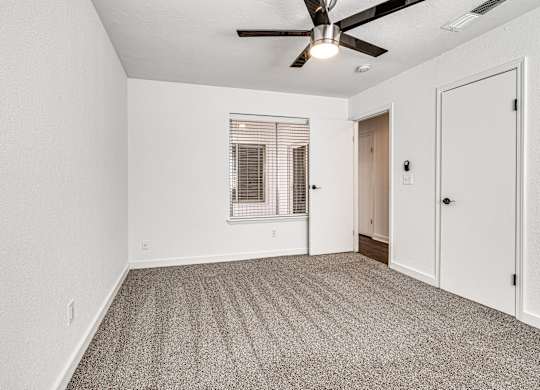 A room with a ceiling fan and carpeted floor.