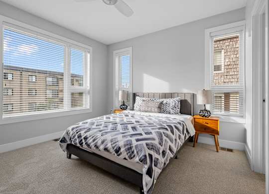 a bedroom with a bed and two windows