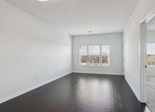 A large empty room with a window and a door.