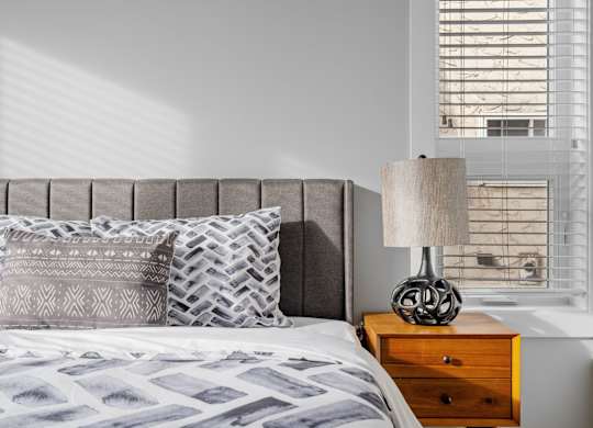a bedroom with a bed and a dresser with a lamp and a window
