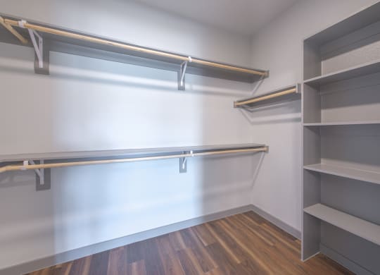 a walk in closet with empty shelves and a white wall