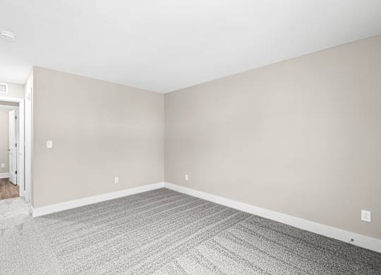 an empty room with white walls and gray carpet