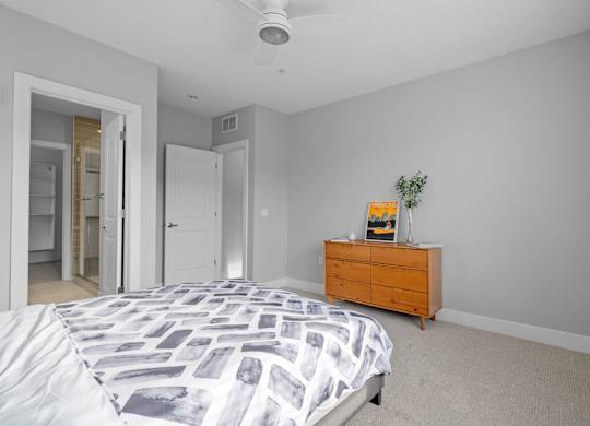 A bedroom with a bed, dresser, and ceiling fan.