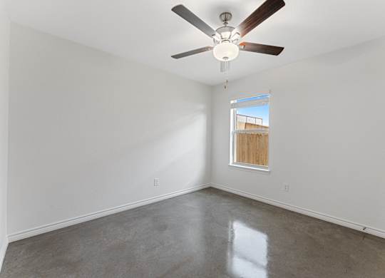 an empty room with a ceiling fan and a window