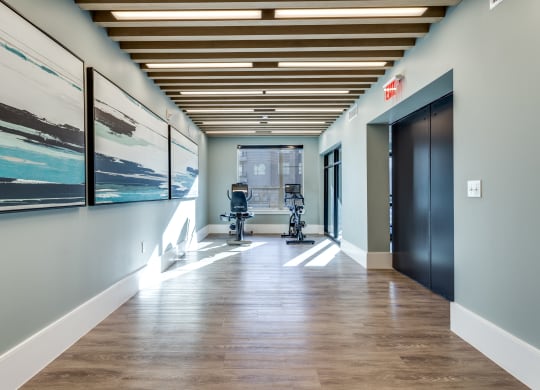 a hallway with a chair and paintings on the wall and a door