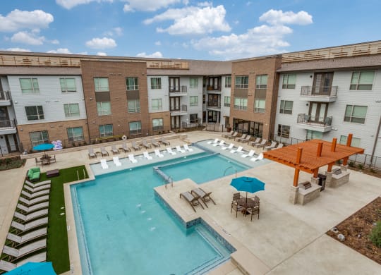 a resort style pool with lounge chairs and umbrellas in front of a building