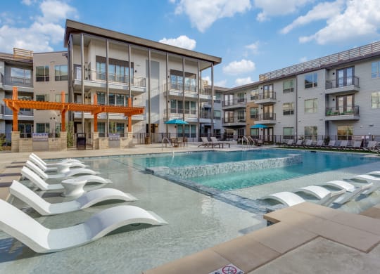 a swimming pool with lounge chairs in front of a building