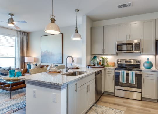 an open kitchen and living room with an island and stainless steel appliances