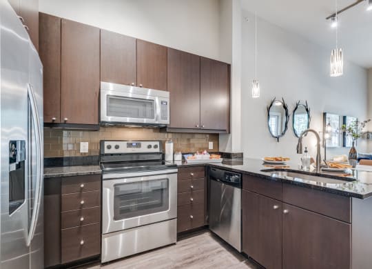 an apartment kitchen with stainless steel appliances and wooden cabinets