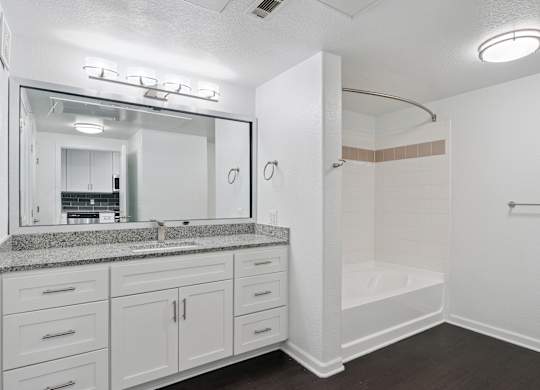 A white bathroom with a sink, mirror, and shower.