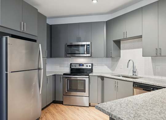 A modern kitchen with stainless steel appliances and a wooden floor.