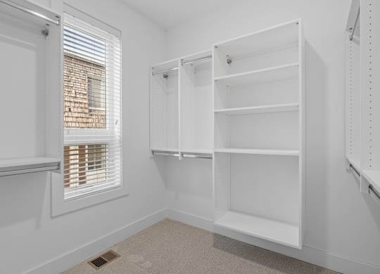 a white closet with white shelves and a window