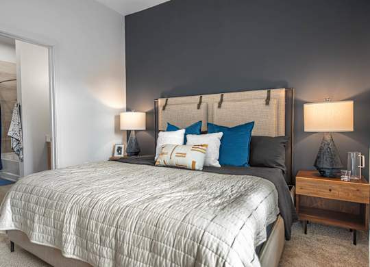 A bedroom with a large bed and a wooden nightstand.