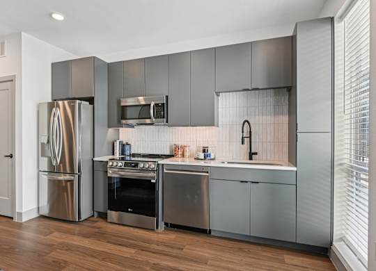 A modern kitchen with stainless steel appliances and wooden floors.