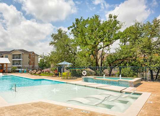 A large outdoor swimming pool with a slide and a fence.
