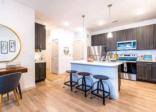 A kitchen with a bar stool and a blue chair.