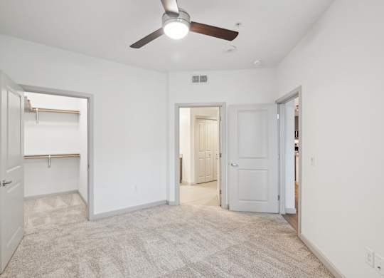 A room with a ceiling fan and carpeted floor.
