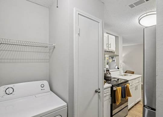 A white washing machine is in a laundry room with a white door.
