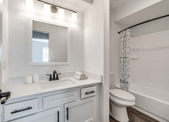 A white bathroom with a toilet, sink, and mirror.