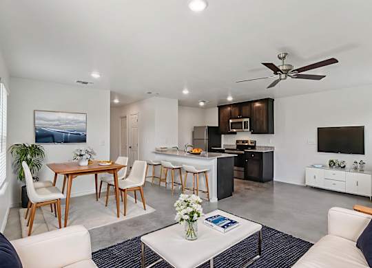 A modern living room with a dining area and kitchen in the background.