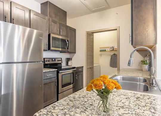 A kitchen with a stainless steel refrigerator, oven, and microwave.