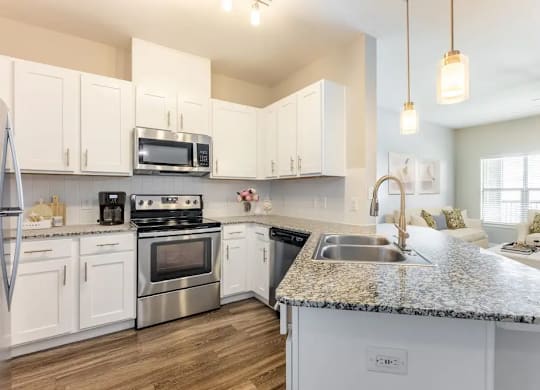 A kitchen with white cabinets and a granite countertop.
