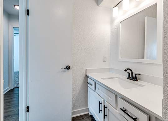 A white bathroom with a sink and mirror.