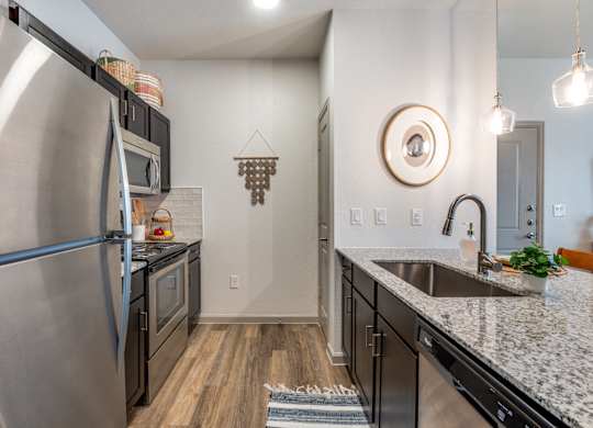A modern kitchen with a stainless steel refrigerator and black cabinets.