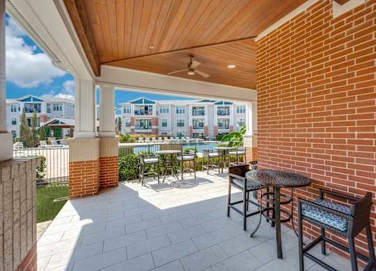 A patio with a table and chairs overlooks a pool and buildings.