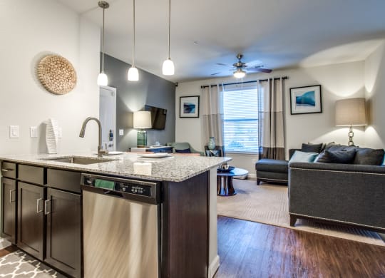 an open kitchen and living room with a couch and a ceiling fan