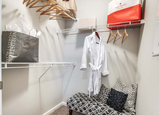 a dressing room with a chair and a closet with clothes
