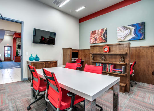 a conference room with a white table and red chairs