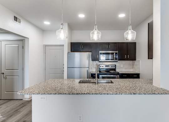 A kitchen with a granite countertop and a microwave above it.