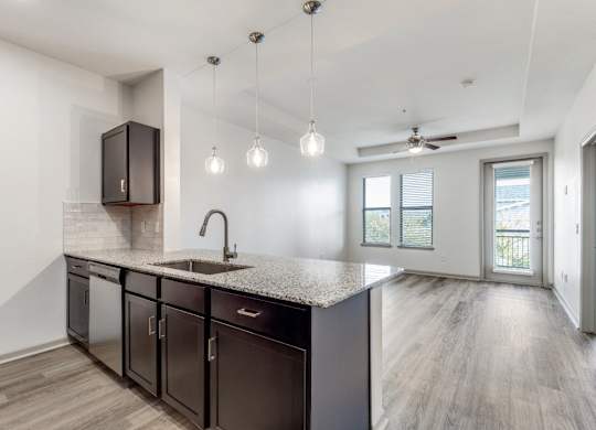 A kitchen with dark brown cabinets and a granite countertop.