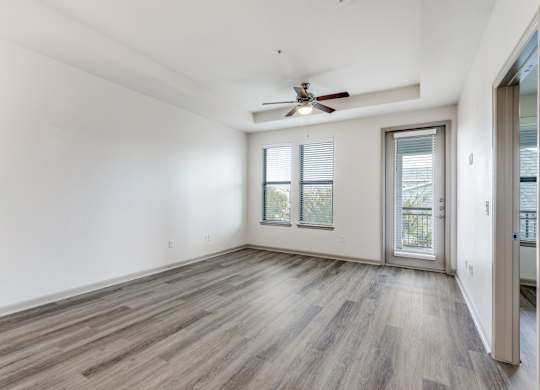 A room with a ceiling fan and sliding glass doors.