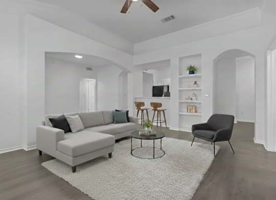 A living room with a grey sofa, a black chair, and a white rug.