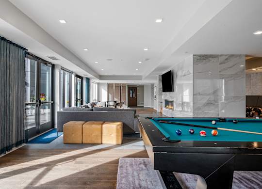 A pool table is in the middle of a room with a bar and a television.