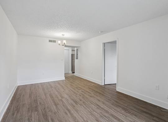 A room with a white ceiling, wooden flooring, and two doors.