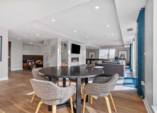 A modern dining room with a black table and grey chairs.